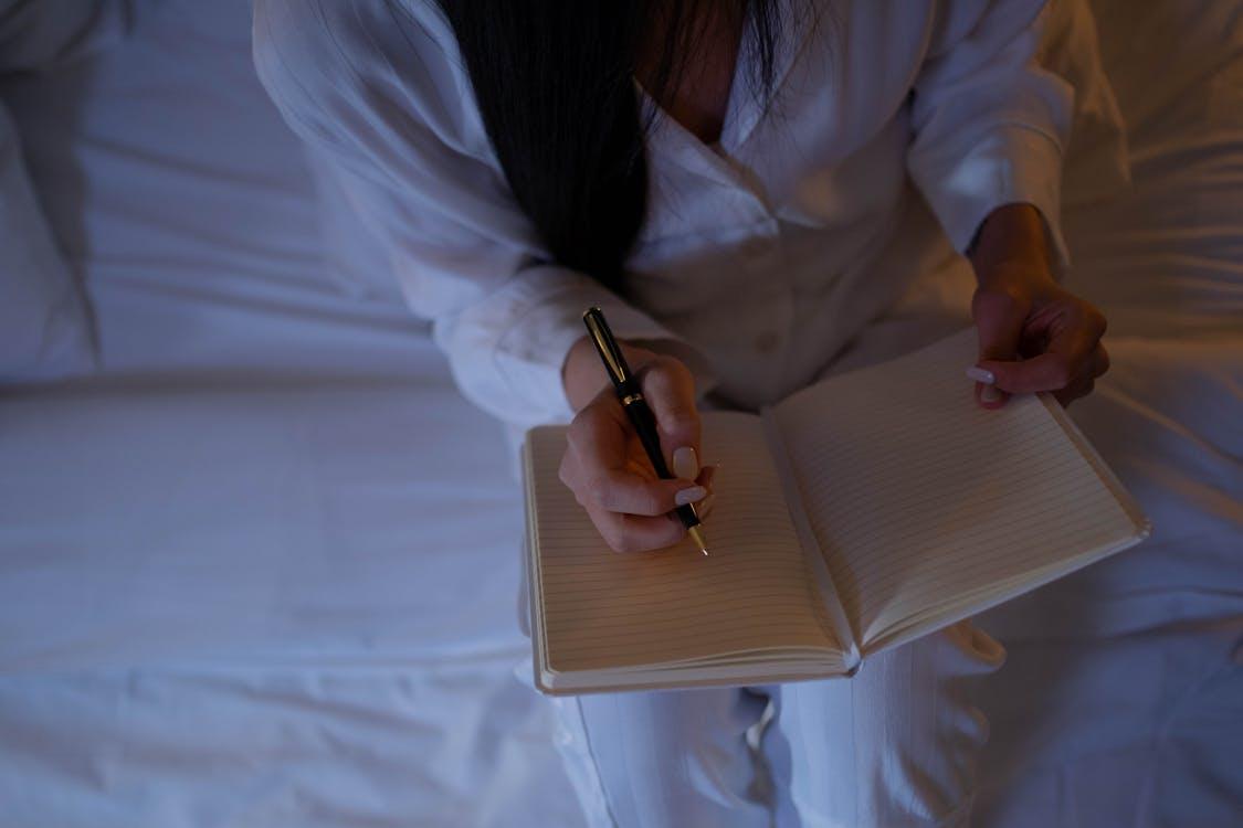 Free Close-Up Shot of a Person Writing on a Notebook Stock Photo